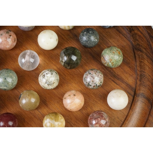 206 - A turned wooden solitaire board complete with polished semi precious stone marbles.