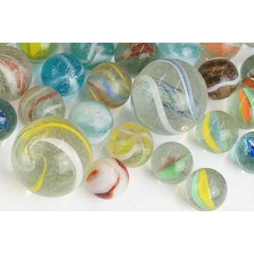 254 - A small collection of vintage glass marbles contained within two bags.