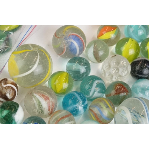 254 - A small collection of vintage glass marbles contained within two bags.