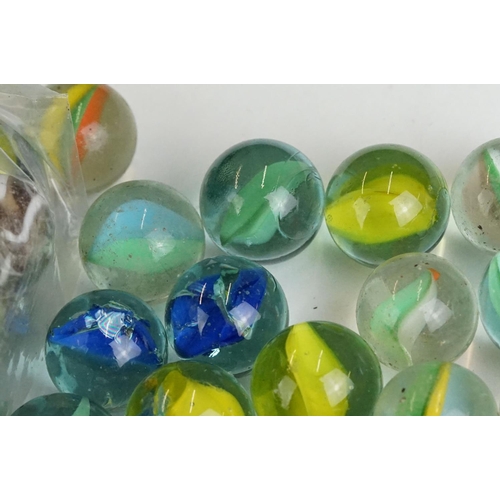 254 - A small collection of vintage glass marbles contained within two bags.