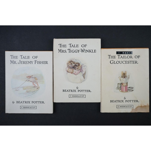 428 - 22 Beatrix Potter hard back books, varying ages, in a wooden display stand