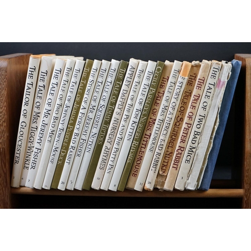 428 - 22 Beatrix Potter hard back books, varying ages, in a wooden display stand