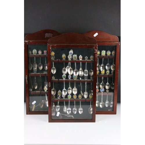 317 - A large collection of souvenir spoons contained within three collectors cabinets.