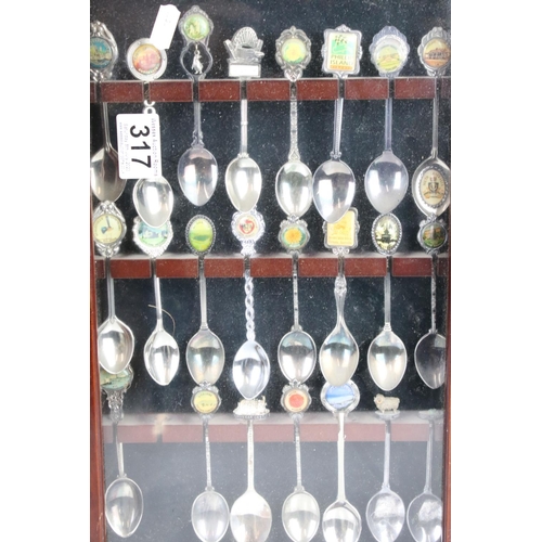 317 - A large collection of souvenir spoons contained within three collectors cabinets.