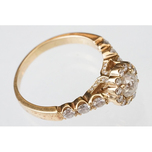 43 - Diamond halo yellow metal ring, the round mixed cut diamond measuring approx 5.6mm x 5.7mm x 4.7mm, ... 