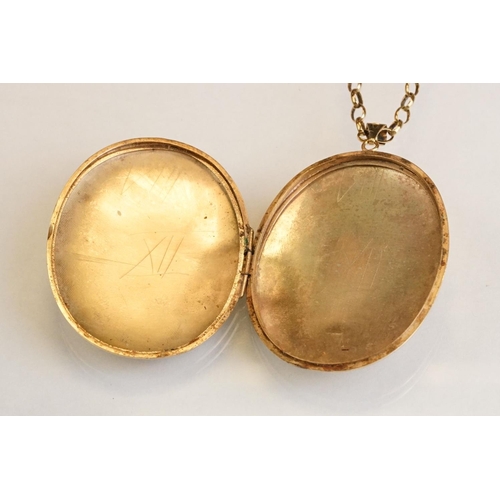 65 - Large yellow metal locket pendant necklace, the oval locket with engraved foliate decoration, dimens... 