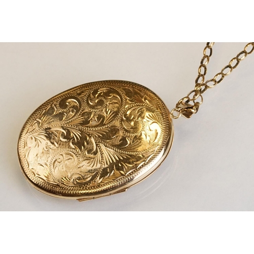 65 - Large yellow metal locket pendant necklace, the oval locket with engraved foliate decoration, dimens... 