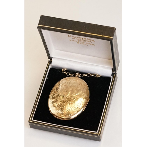 65 - Large yellow metal locket pendant necklace, the oval locket with engraved foliate decoration, dimens... 