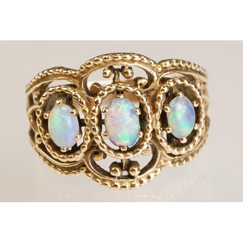 67 - Opal yellow metal three stone ring, three oval cabochon cut Ethiopian opals, displaying violet, blue... 