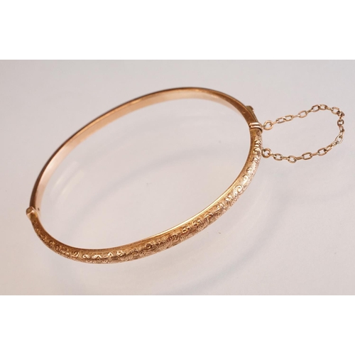69 - Late 19th century 9ct rose gold hinged bangle, chased foliate scroll decoration to the upper half, t... 