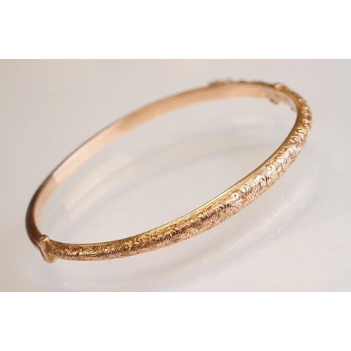 69 - Late 19th century 9ct rose gold hinged bangle, chased foliate scroll decoration to the upper half, t... 
