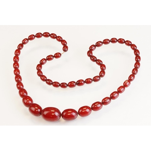 73 - Cherry Bakelite amber graduated bead necklace, comprising fifty-six beads, the largest bead measurin... 