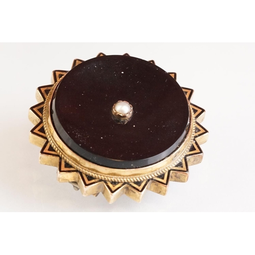 74 - Late 19th century onyx, seed pearl and black enamel yellow metal brooch, glazed panel verso, hinged ... 