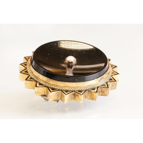 74 - Late 19th century onyx, seed pearl and black enamel yellow metal brooch, glazed panel verso, hinged ... 