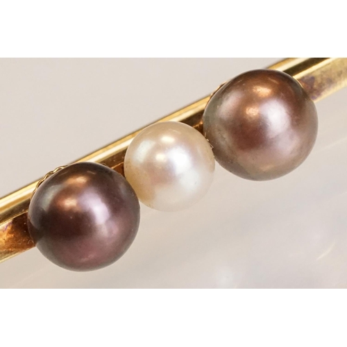 76 - Cultured pearl 14ct yellow gold bar brooch, white pearl to centre and two black pearls, trombone cla... 