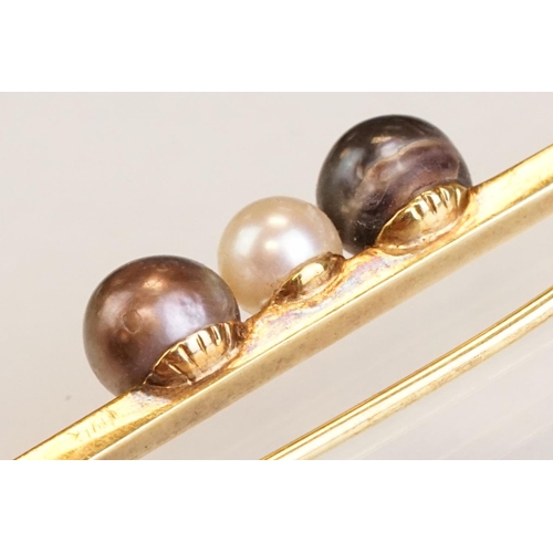76 - Cultured pearl 14ct yellow gold bar brooch, white pearl to centre and two black pearls, trombone cla... 