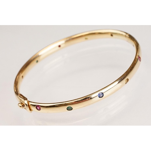 82 - Gem set 18ct yellow gold hinged bangle, pink, blue and yellow small round brilliant cut sapphires an... 