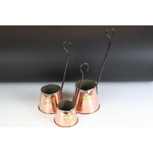131 - Three early 20th Century copper and cast iron cider measures each of tapering form with brass labels... 