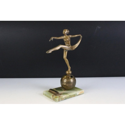 142 - Art Deco gilt metal table lighter in the form of a semi-nude lady dancer raised upon a globe, green ... 