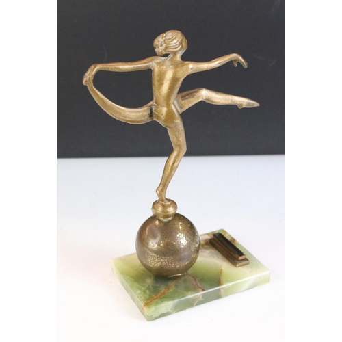 142 - Art Deco gilt metal table lighter in the form of a semi-nude lady dancer raised upon a globe, green ... 