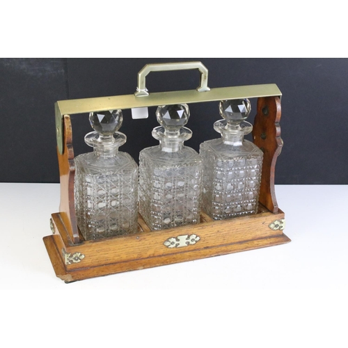 174 - Early 20th Century oak tantalus housing three cut glass decanters with faceted stoppers. Marked C702... 