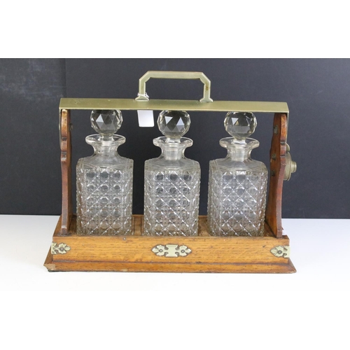 174 - Early 20th Century oak tantalus housing three cut glass decanters with faceted stoppers. Marked C702... 