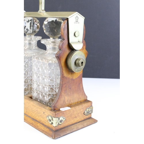 174 - Early 20th Century oak tantalus housing three cut glass decanters with faceted stoppers. Marked C702... 