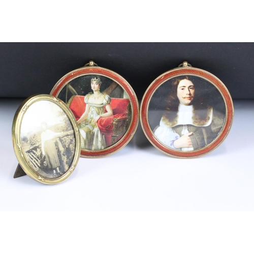 219 - A pair of antique brass and enamel round frames together with another brass frame.