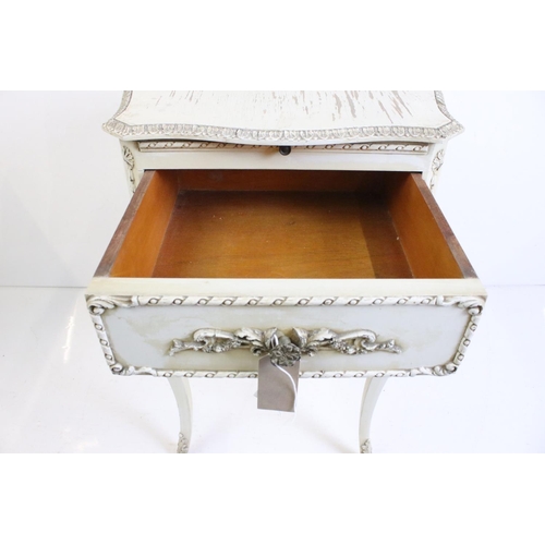 483 - Two French style Cream Painted Bedside Cabinets with moulded floral and foliate decoration, one with... 