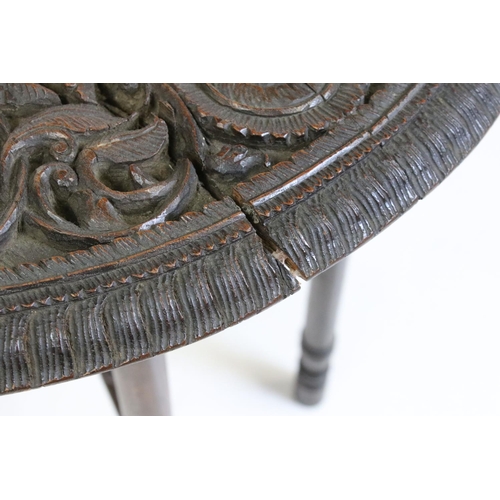 538 - Indian Hardwood Circular Table, the top profusely carved with foliate scrolling, raised in a folding... 