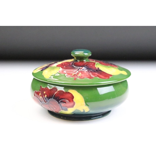 10 - 20th Century Moorcroft lidded pot featuring tube lined hibiscus flowers with a squat body and finial... 