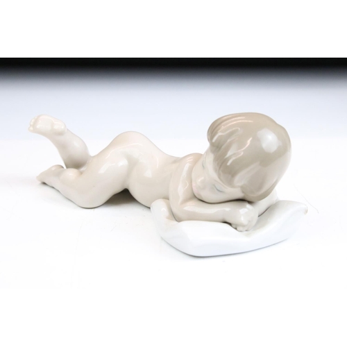 74 - Four Lladro ceramic figurines to include a sleeping baby, swan, girl with puppies and yawning boy. A... 