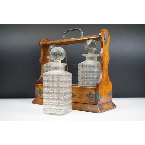 163 - An antique oak tantalus with silver plated mounts with three glass decanters.