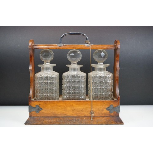 163 - An antique oak tantalus with silver plated mounts with three glass decanters.