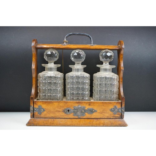 163 - An antique oak tantalus with silver plated mounts with three glass decanters.