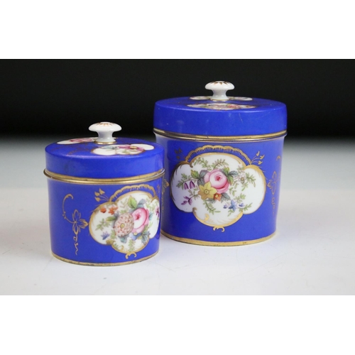 57 - Two porcelian dressing table pots, each having a blue ground with hand painted floral panels. Unmark... 