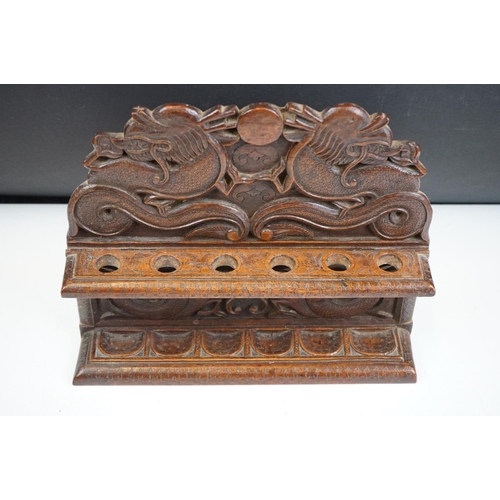 147 - An oriental carved wooden pipe rack with dragon decoration together with a pipe with Viking bowl.