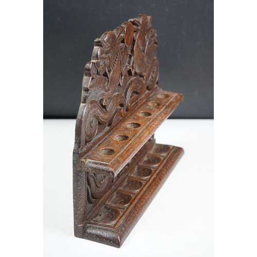 147 - An oriental carved wooden pipe rack with dragon decoration together with a pipe with Viking bowl.