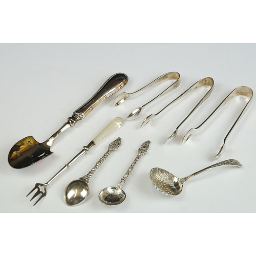 208 - Three silver sugar tongs, a millennium cheese scoop and other spoons