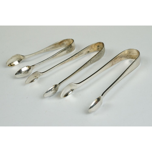 208 - Three silver sugar tongs, a millennium cheese scoop and other spoons