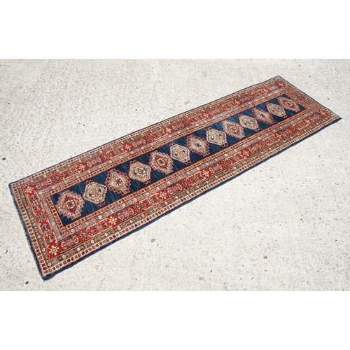 585 - Eastern Red and Blue Ground Wool Runner Rug decorated with thirteen guls within a deep border, appro... 