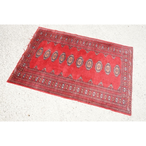 596 - Eastern Red Ground Wool Rug decorated with a row of ten guls within a border, approx. 190cm x 130cm