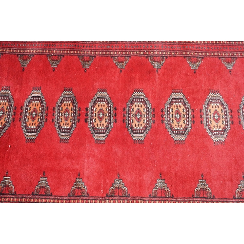 596 - Eastern Red Ground Wool Rug decorated with a row of ten guls within a border, approx. 190cm x 130cm