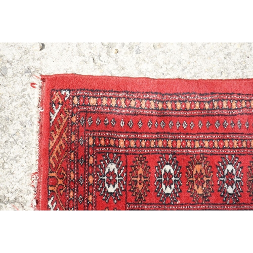 596 - Eastern Red Ground Wool Rug decorated with a row of ten guls within a border, approx. 190cm x 130cm