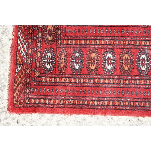 596 - Eastern Red Ground Wool Rug decorated with a row of ten guls within a border, approx. 190cm x 130cm