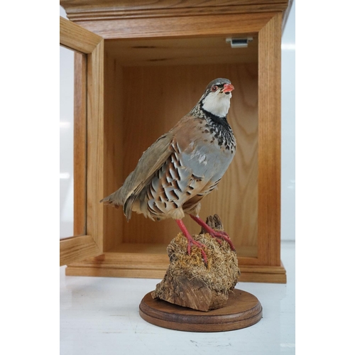 166 - Taxidermy Red Partridge perched on a mossy log to base, set within a glass doored display cabinet. M... 