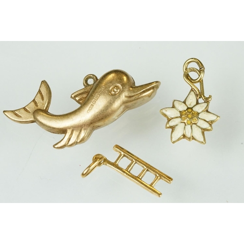 105 - 9ct yellow gold dolphin charm; a yellow metal ladder charm indistinctly stamped 750; and an enamelle... 