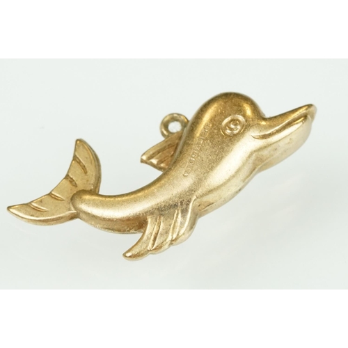 105 - 9ct yellow gold dolphin charm; a yellow metal ladder charm indistinctly stamped 750; and an enamelle... 