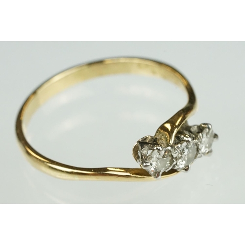 123 - Diamond three stone yellow metal ring, three graduated small round cut diamonds, claw set, crossover... 