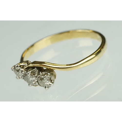 123 - Diamond three stone yellow metal ring, three graduated small round cut diamonds, claw set, crossover... 